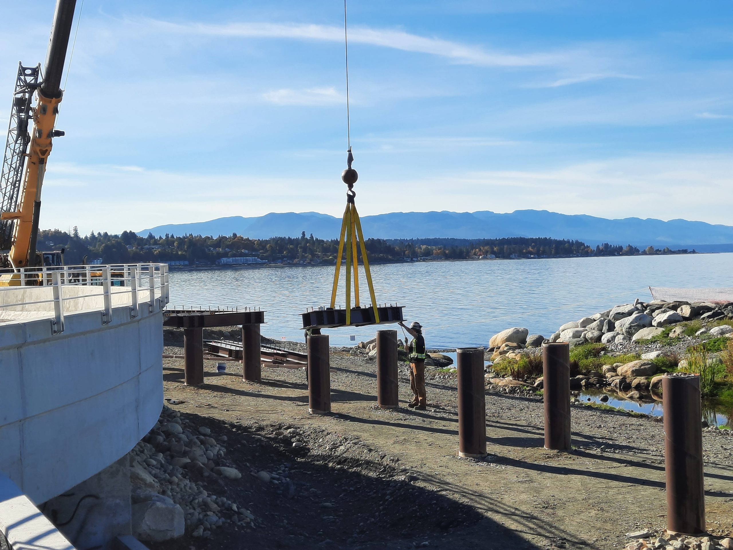 The Waterfront Viewing Platform and Walkway being built, showing a crane lower down materials and a construction worker guiding it.