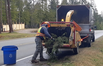 Image of Qualicum Beach crews feeding branches into a wood chipper