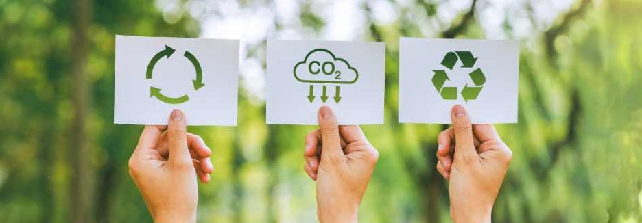 Three hands holding up papers featuring environmental symbols, with trees in the background.