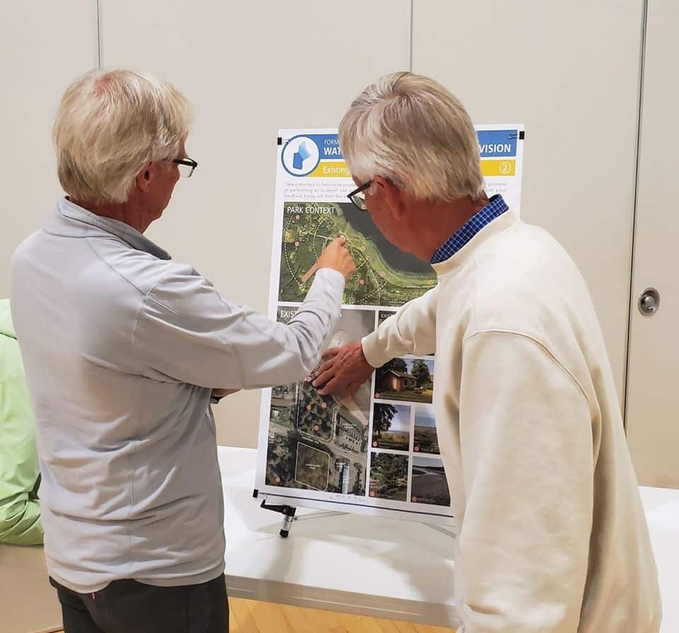 Two elderly people reviewing a large infographic of government plans.