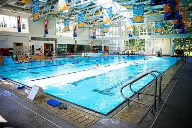 Interior view of Ravensong Aquatic Centre with a bright swimming pool, multiple lanes for lap swimming, and large windows allowing natural light.