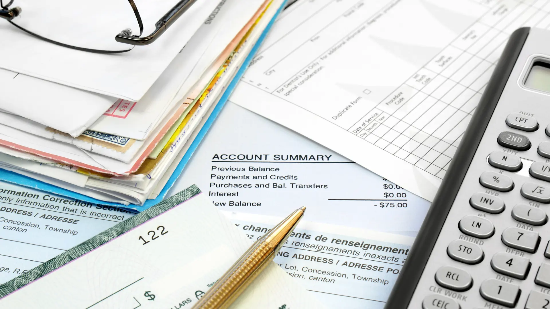 Stacks of paperwork on a table with a calculator and pen on top.