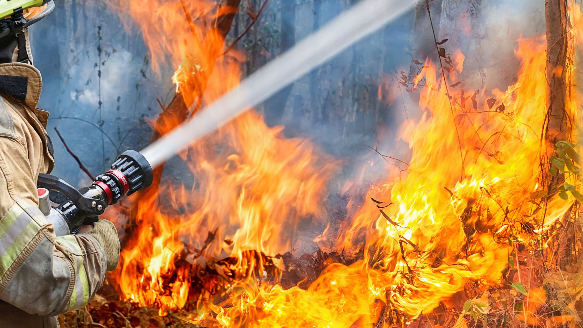 Firefighter aiming water at a wildfire