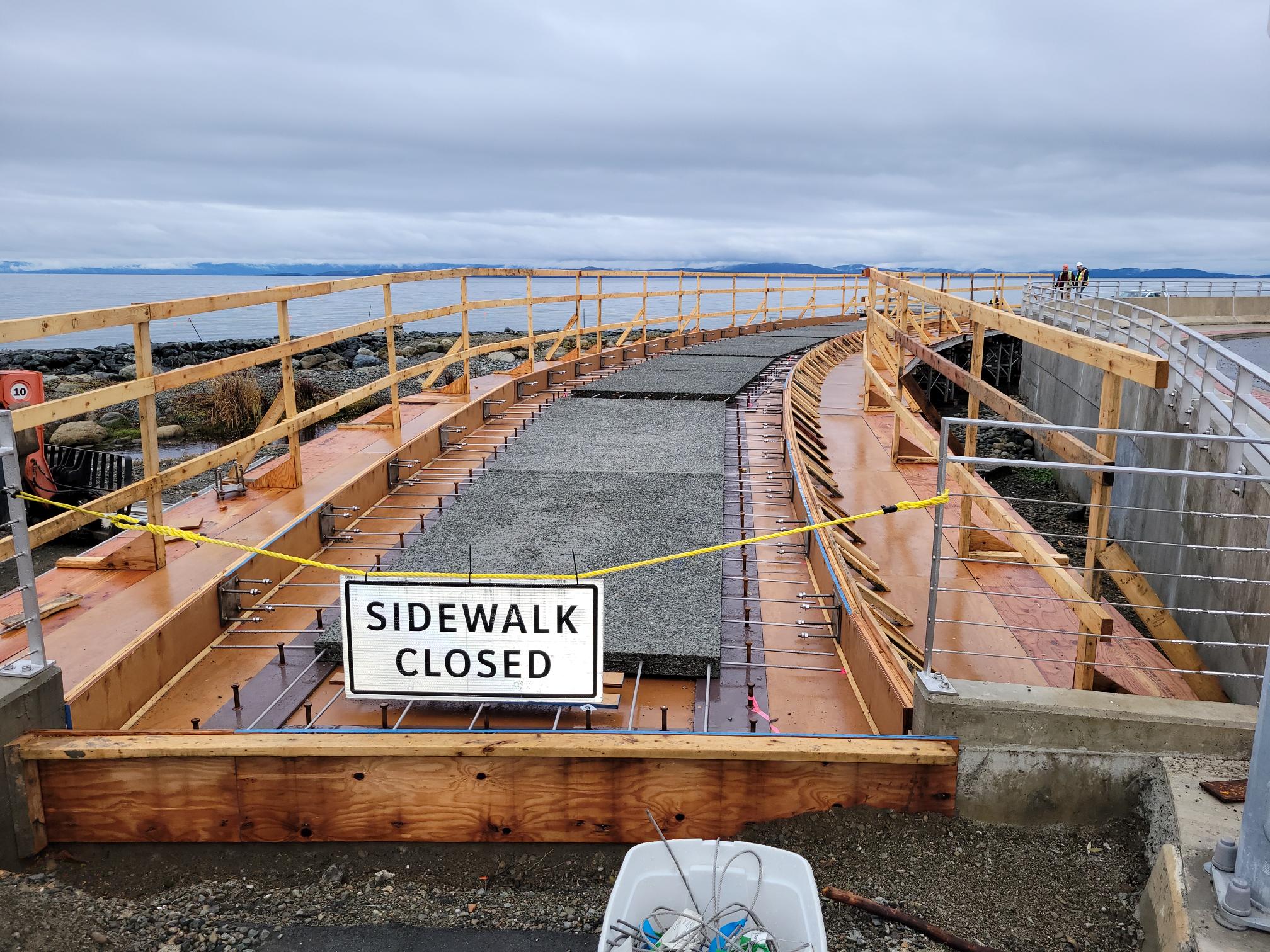 The Waterfront Viewing Platform and Walkway being built, with a sign reading 'Sidewalk Closed'.