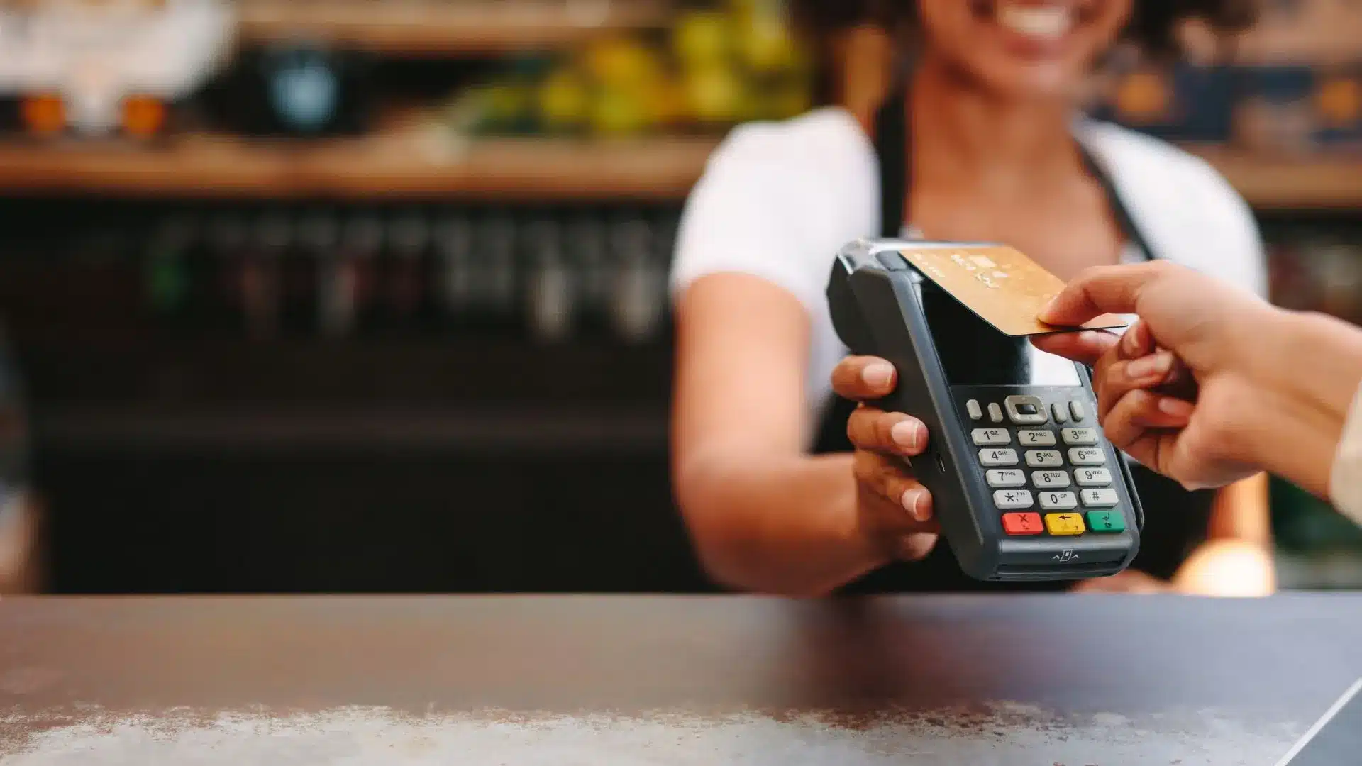 Person tapping credit card on a card reader to pay for purchase.