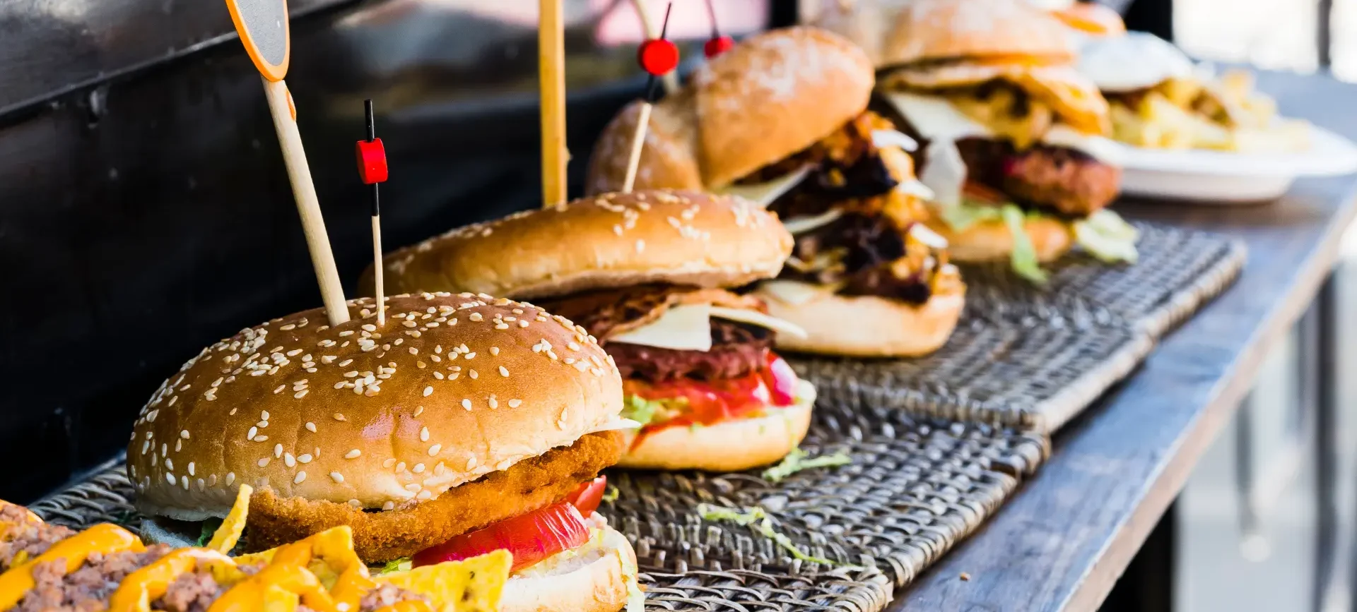 Four hamburgers on a shelf attached to a food truck.