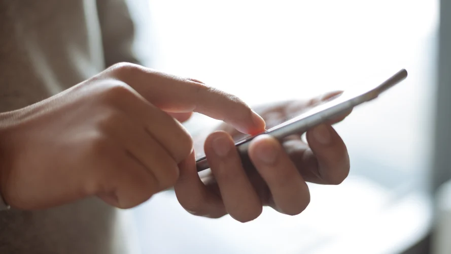 Person typing on cell phone with right pointer finger.