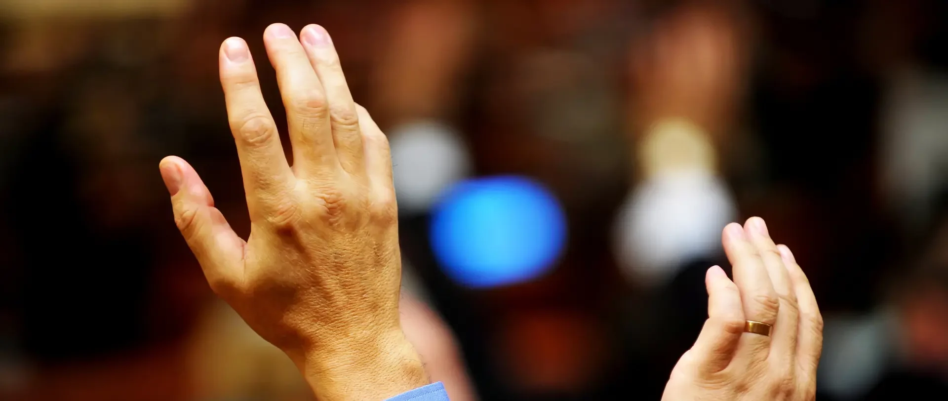 Two raised hands with a blurred background.